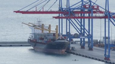 Liman turnaları denize açılmadan önce konteynırları bir gemiye yüklüyorlar