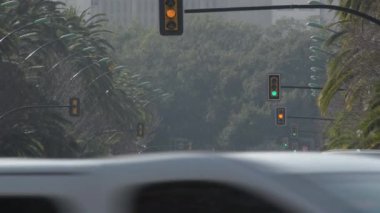 Gün batımında şehir caddesinde trafik ışıkları ve arabalar dolaşır.
