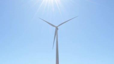 Rüzgar türbini mavi gökyüzüyle güneşli bir günde hareket ediyor