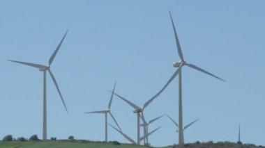 Yenilenebilir enerji türbinleri bir tepede pervaneleri hareket ettiriyor.