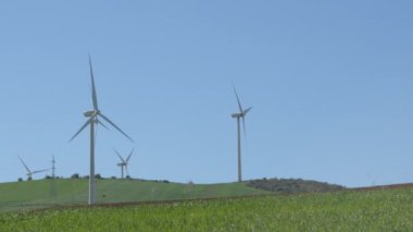 Rüzgâr türbinleri enerjiyi hareket ettirir. Mavi gökyüzü güneşli bir günde bıçakları hareket ettirir.