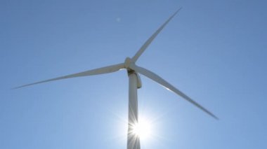 Yenilenebilir enerji türbini, güneşli bir günde mavi gökyüzünde gün ışığıyla hareket ediyor.