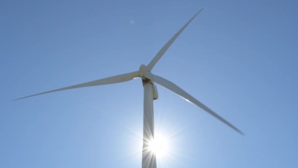 青い空に太陽光で動く再生可能エネルギーの風力タービン晴れた日 — ストック動画