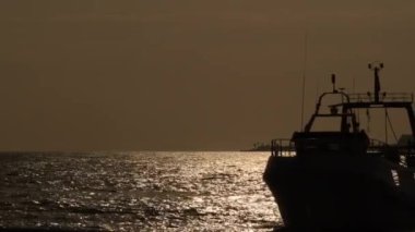 Balıkçı gemisi gün batımında limana giriyor.
