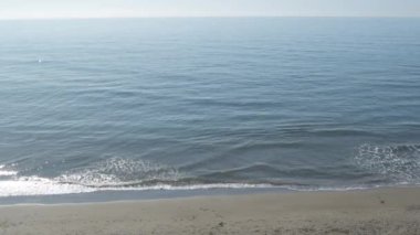 Mavi deniz dalgaları güneşli bir günde sahile geliyor.