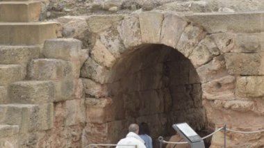 İnsanlar antik Roma tiyatrosunda bir taş kemeri ziyaret ediyorlar.