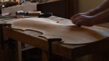 Luthier yeni bir kemanın kapağını zımparalıyor.