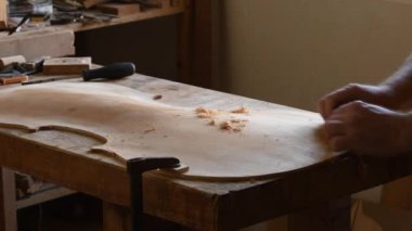 Luthier bir keman çellosunun kapağında çalışıyor.