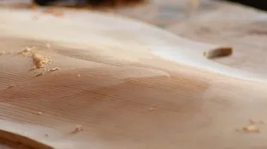 Luthier yeni bir müzik aletinin kapağını zımparalıyor.