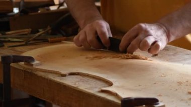 Luthier iş yerinde yeni bir kemancı zımparalıyor.