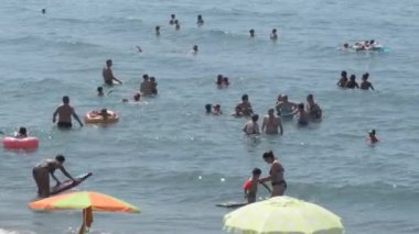 İnsanlar kumsalda güneşli bir yaz günü banyo yapıyorlar.