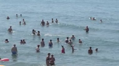 İnsanlar kumsalda güneşli bir yaz günü banyo yapıyorlar.