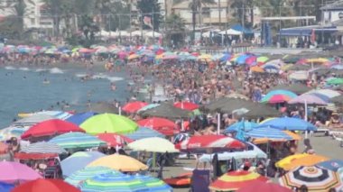 Yazın güneşli bir gününde, Akdeniz insanlarla ve şemsiyelerle dolu.