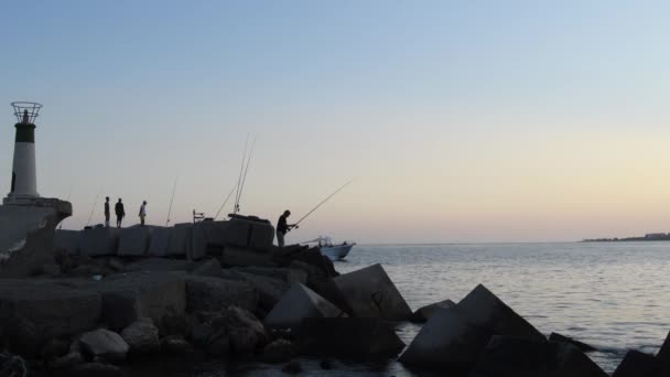 Pêcheurs pêchant dans un port au coucher du soleil