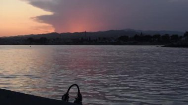 Önünde bir köy olan bir balıkçı limanında gün batımı