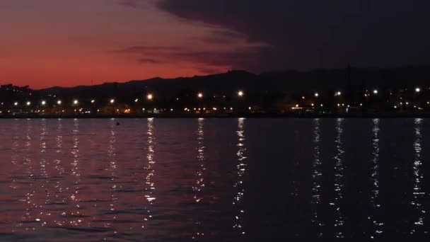 Lumières d'un village marin reflétées dans une vague de la plage au crépuscule