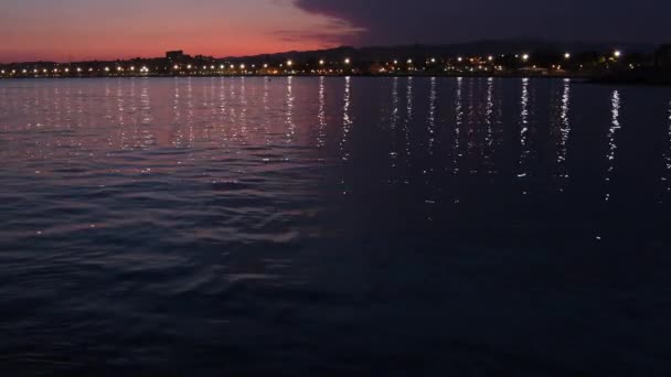 穏やかな夜の夕暮れ時にビーチに反映された海洋村の光 — ストック動画