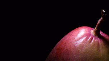 Siyah arka planda kırmızı mango meyveleri dönüyor