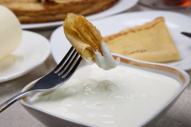 Ekşi krema bir çatal üzerinde krep parçası.