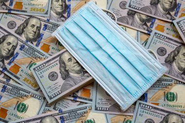Amerika Birleşik Devletleri banknotları ve virüse karşı koruyucu bir maske. Coronovirüs ile ilişkili dünya ekonomik krizi.