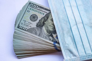 Amerika Birleşik Devletleri banknotları ve virüse karşı koruyucu bir maske. Coronovirüs ile ilişkili dünya ekonomik krizi.