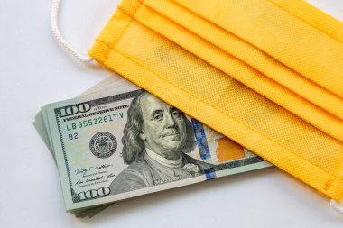 Amerika Birleşik Devletleri banknotları ve virüse karşı koruyucu bir maske. Coronovirüs ile ilişkili dünya ekonomik krizi.