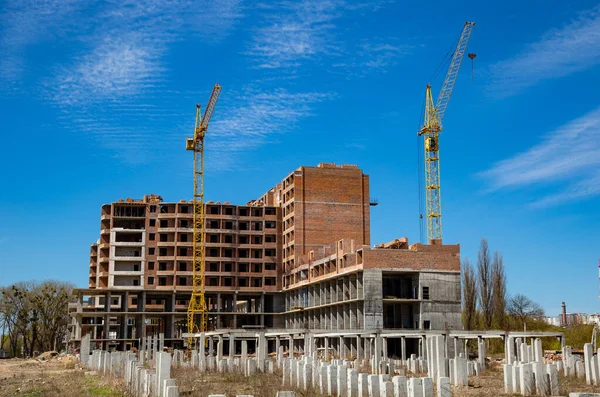 Work in progress on a new apartment block. Tall building under construction with cranes. Construction Site of New Building.