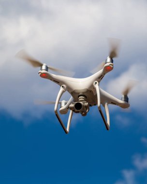 Mavi gökyüzüne karşı uçan bir kuadkopter..