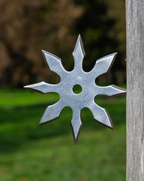 Shuriken (throwing star), traditional japanese ninja cold weapon stuck in wooden background.