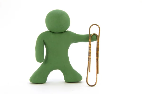 Groene plasticine karakter en grote paperclip. Briefpapier. Geïsoleerd op witte achtergrond — Stockfoto