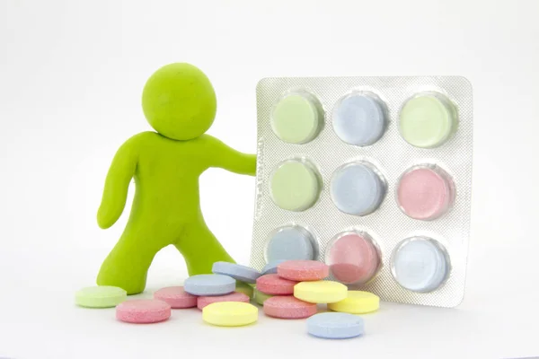 Caráter de plasticina verde limão e comprimidos coloridos na embalagem. Tema da farmácia. Isolado sobre fundo branco — Fotografia de Stock