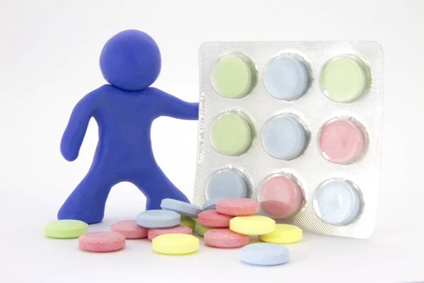 Carattere di plastilina blu e compresse di pillole colorate nella confezione. Tema farmacia. Isolato su sfondo bianco — Foto Stock