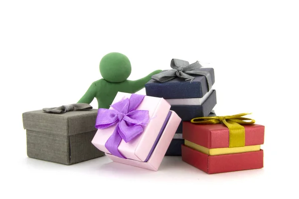 Carácter de plastilina verde y cajas de regalo sobre fondo blanco. Cajas de regalos. Concepto de vacaciones . —  Fotos de Stock