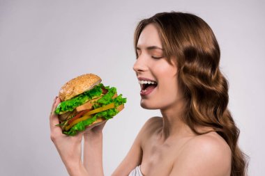 Mutlu kız izole hamburger yiyor.