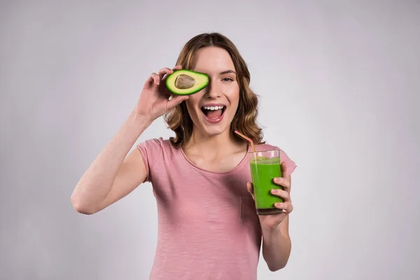 Дівчина позує з зеленим соком і авокадо ізольовані . — стокове фото
