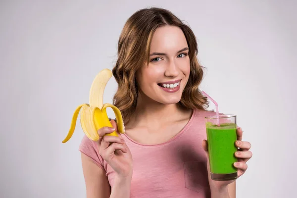 Дівчина позує з зеленим соком і бананом ізольовані . — стокове фото