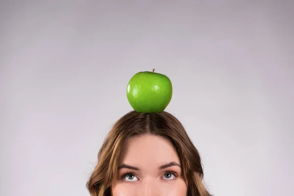 Dziewczyna pozuje z zielonego jabłka uśmiechający się na białym tle. — Zdjęcie stockowe