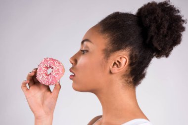 Afro-Amerikan kız izole donut yemek.