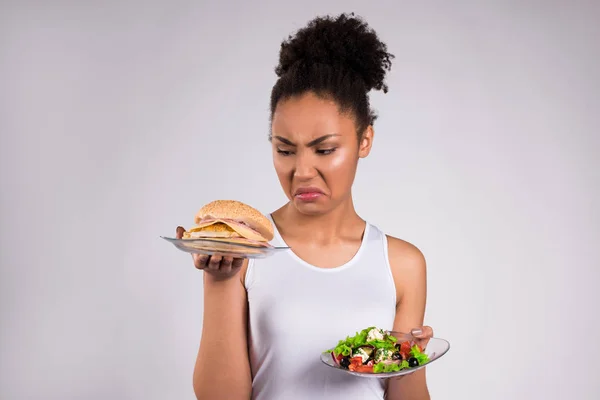 Черная девушка держит чизбургер и салат изолированы — стоковое фото