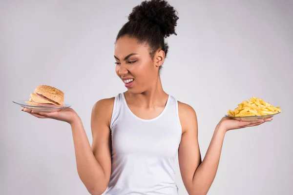 Черная девушка держит чизбургер и картошку фри изолированы — стоковое фото