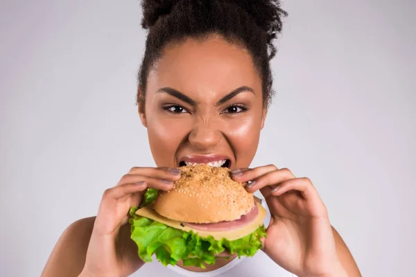 Афро-американская девушка ест гамбургер изолирован . — стоковое фото