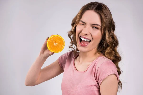 Щаслива дівчина позує з апельсином, посміхаючись ізольовано . — стокове фото