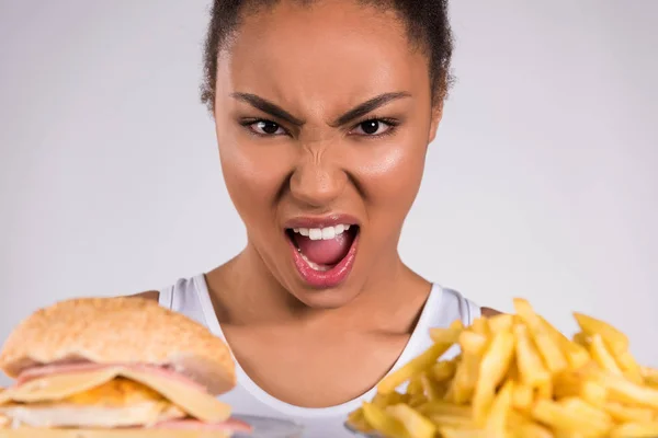 Черная девушка держит чизбургер и картошку фри изолированы — стоковое фото