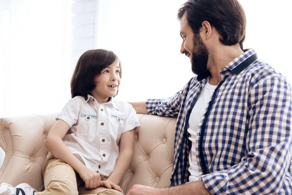 Bärtiger Vater kommuniziert mit Teenager-Sohn auf Couch. — Stockfoto