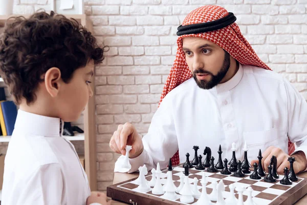 Arabian bearded father and little son play chess. — Stock Photo, Image