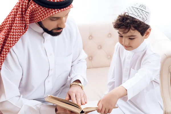 Arabian bearded man is reading book with small son. — Stock Photo, Image