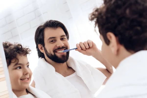 Happy father and son brush teeth with toothbrush, looking in mirror. — Stock Photo, Image