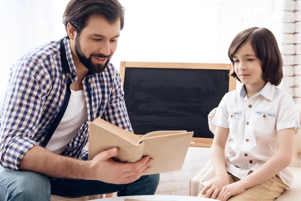 Père barbu avec fils heureux lit livre assis sur le canapé . — Photo