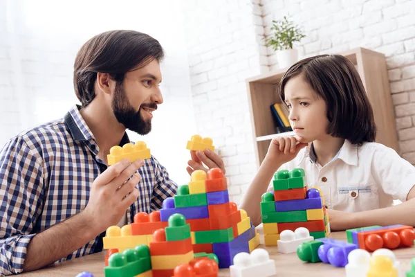 Père heureux et fils jouent avec des blocs en plastique colorés . — Photo