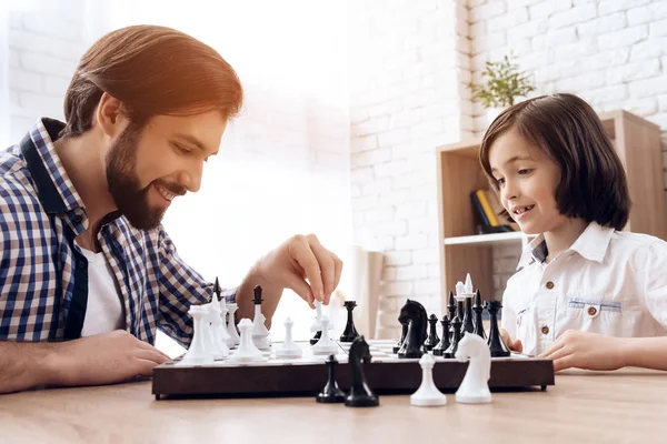 Adulte barbu père joue aux échecs avec adolescent fils à la maison . — Photo